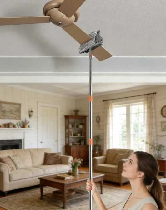 Woman reaching a ceiling fan blade from the floor with the Fonoran ceiling fan duster on a long extension pole in a living room